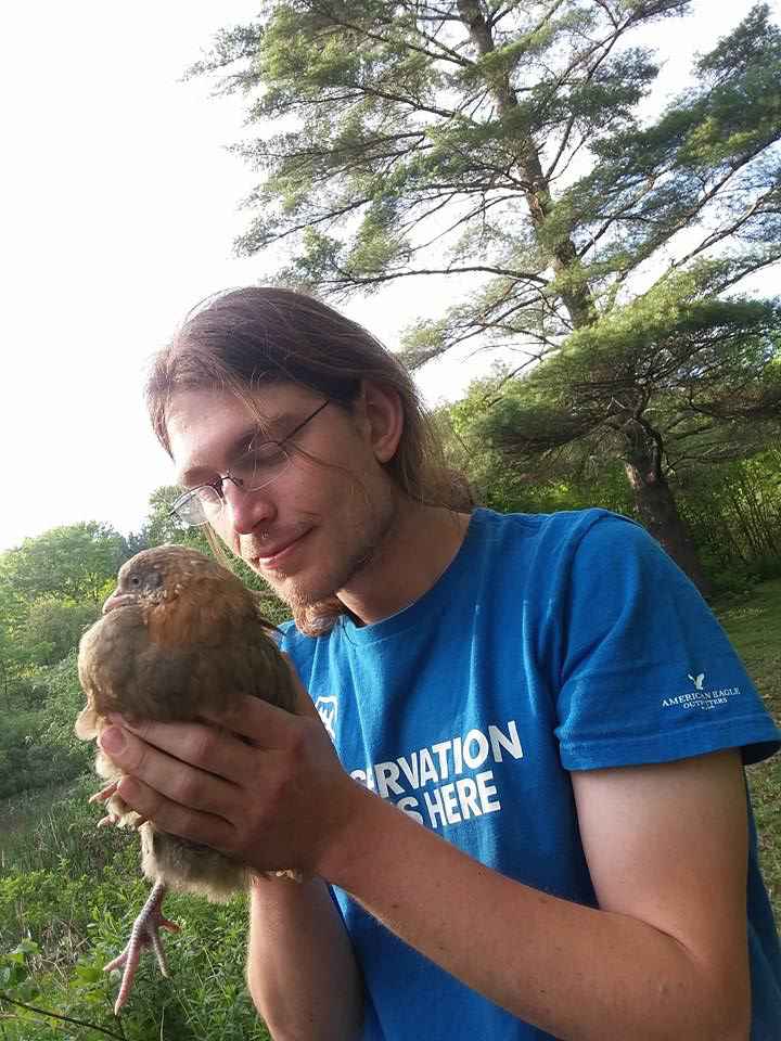 Christopher Griffin holding a small brown chicken.